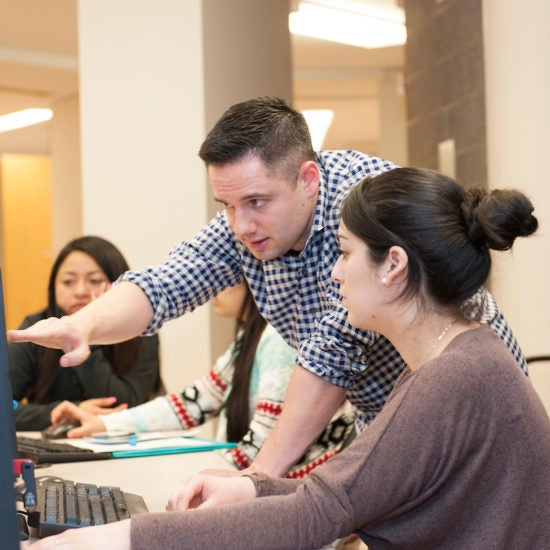 A tutor works with a student at a computer.