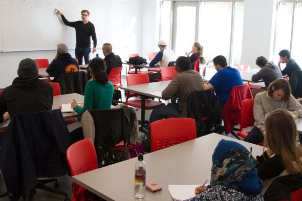 Instructor points at whiteboard while students take notes