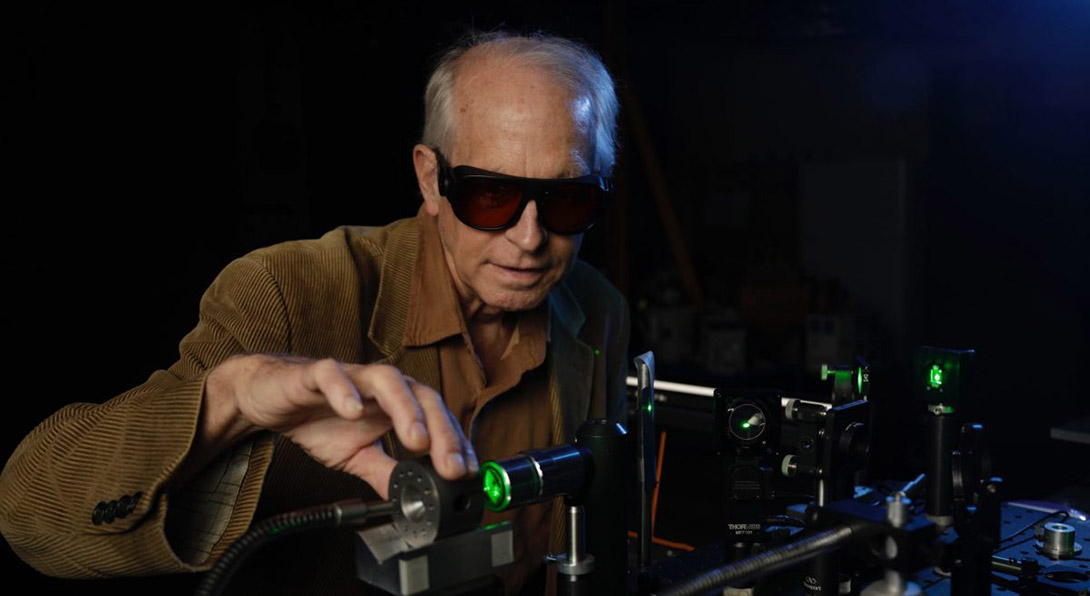 Russell Hemley wearing safety glasses and working on a scientific instrument